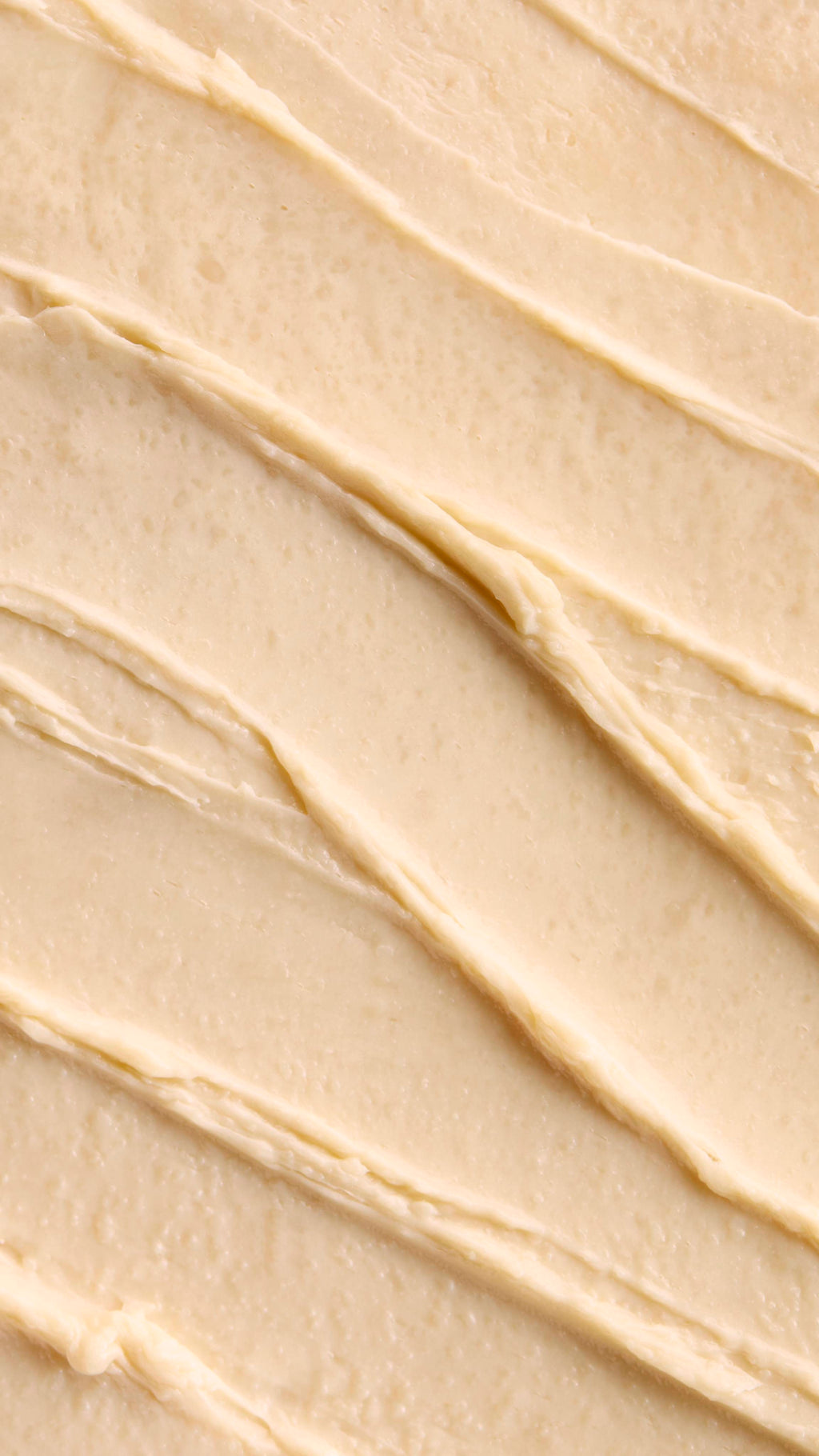 A close-up of a Super Milk Shampoo with distinct, diagonal ridges and soft peaks. The texture suggests a rich, thick consistency, creating a visually pleasing and inviting pattern of smooth swirls.
