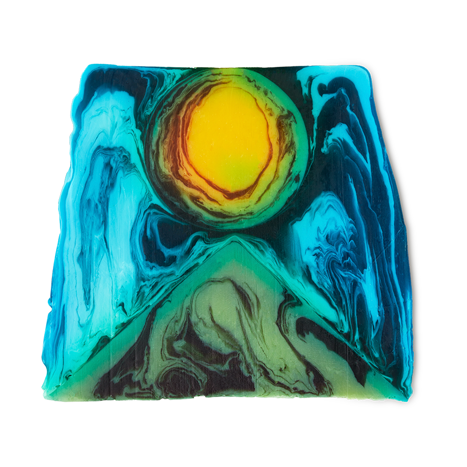 Alban Hefin is a thick, off-square slice of soap. An abstract design shows a green, pyramid-like shape at the bottom with a bright yellow, sun-like circle, surrounded by blue swirls.