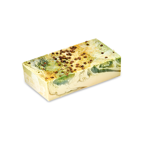 A rectangular bar of Baklava handmade soap with a cream base and marbled swirls of green and gold. The top is sprinkled with dark brown spice seeds, set against a solid black background.