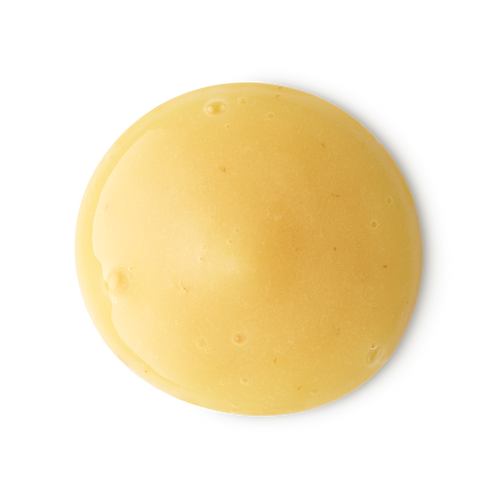 A smooth, circular dollop of creamy yellow shower gel with a glossy finish. The thick, opaque liquid features tiny air bubbles and is centered against a clean, neutral grey background.