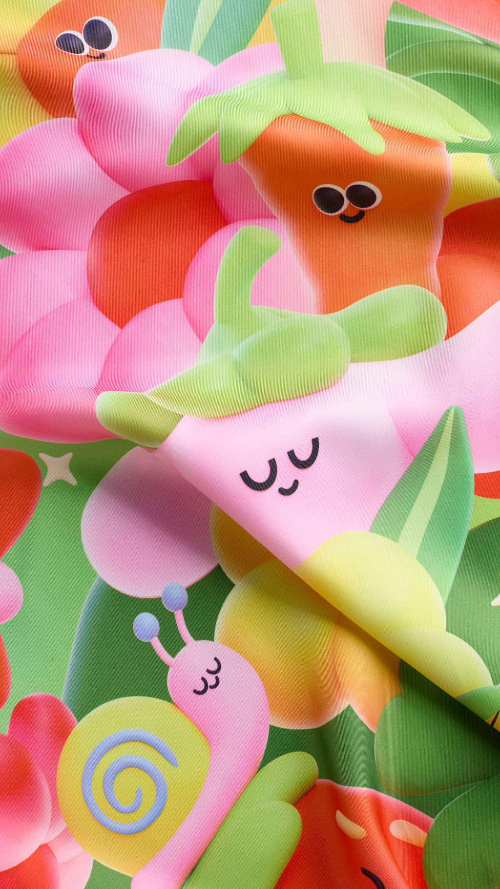 A super close-up shot of the "Blooming Lovely" fabric Knot Wrap featuring colourful, 3D-style garden illustrations. A pink snail and a smiling pink flower are visible amongst other cheerful, soft-focus garden characters.