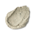 Earthy, Woody, Karma. A thick, textured dollop of pale beige foot mask. The product has a dense, matte consistency with visible dark exfoliating flecks and small lumps, showing a swirled and slightly peaked surface.