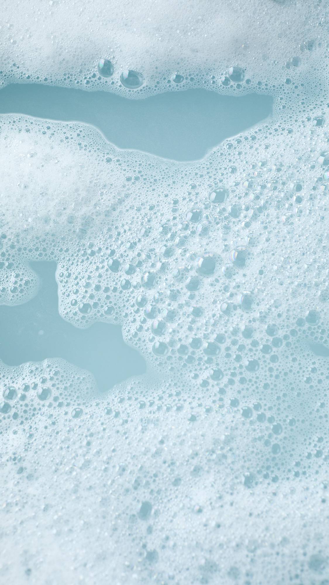 The image shows the colourful aftermath of using the Frozen reusable bubble bark stick. There is turquoise, icy-blue bath water surrounded by mountains of bright bubbles.