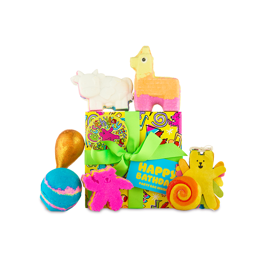 Happy Bathday. A bright yellow wrapped gift box with lime green ribbon and playful paper sits surrounded by six colourful Lush bathing products and extra decorations.