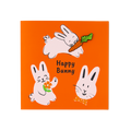 Happy Bunny. An orange greeting card features three hand-drawn pink rabbits and the text "Happy Bunny". One rabbit carries a carrot, another holds an orange flower, and a third wears a polka-dot bow tie. The carrot is a removable pin badge.
