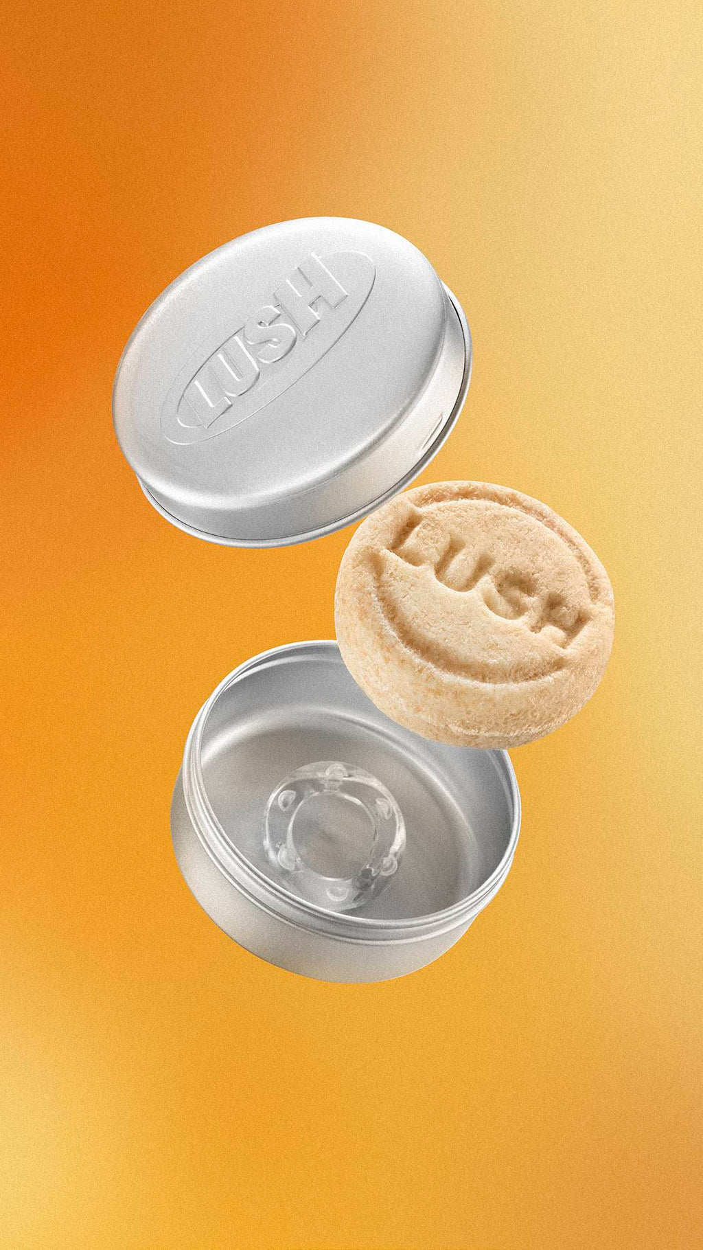 A round, textured beige Lush solid shampoo bar floats mid-air between an open, round silver aluminium tin. The tin lid is embossed with the "LUSH" logo. The background is a soft, metallic gold gradient.