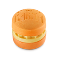 Karma. An orange, circular bath bomb shaped like a macaron with a creamy yellow middle layer of solid oil. The word 'KARMA' is embossed on the top surface, which is dusted with a fine gold shimmer.