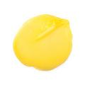 Marilyn. A smooth, round dollop of bright yellow hair treatment. The product has a glossy, fluid texture with subtle folds and a slight peak on one side where it was swirled.