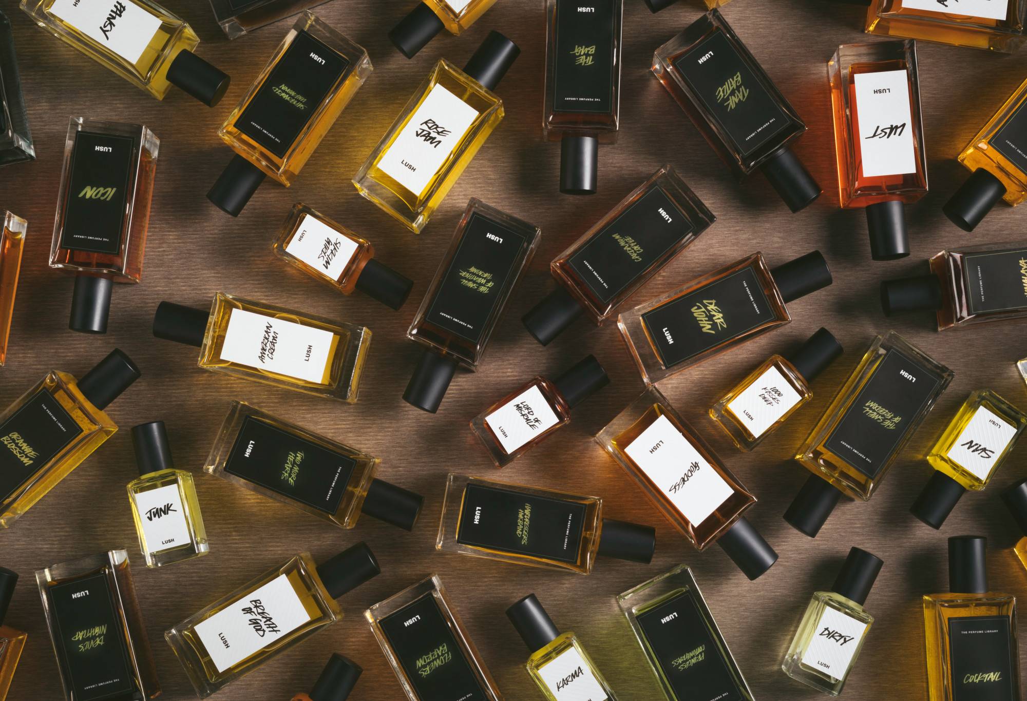 A selection of white and black label perfume bottles are arranged randomly on a dark wooden surface.
