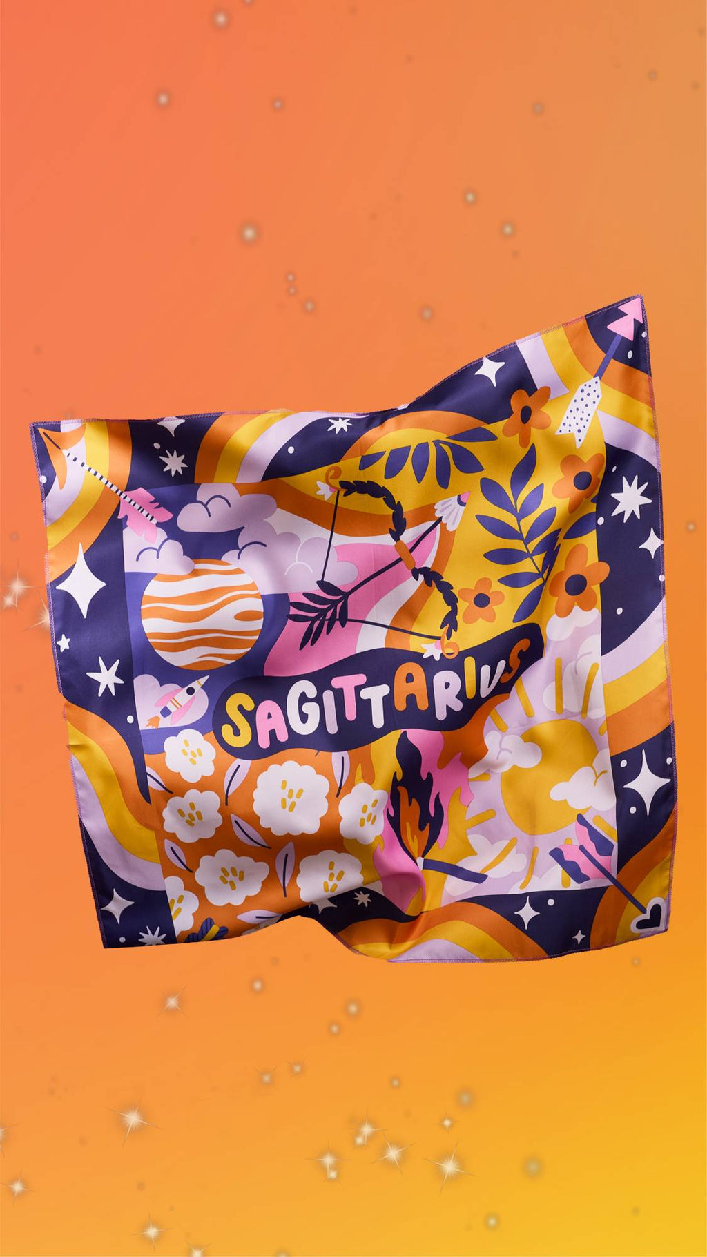 The image shows a yellow and orange blurred background scattered with sparkles. The Sagittarius knot wrap is floating with the design facing the camera showing the shimmering, silky texture of the fabric.
