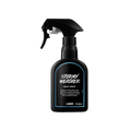 A recycled black plastic LUSH body spray bottle with a trigger nozzle stands upright with a deep blue rimmed label with white text that reads "Stormy Weather Body Spray".