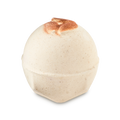 Super Milk. A spherical, off-white bath bomb with a speckled texture and flat, geometric base. The top features three embossed, decorative, shimmering bronze almonds.