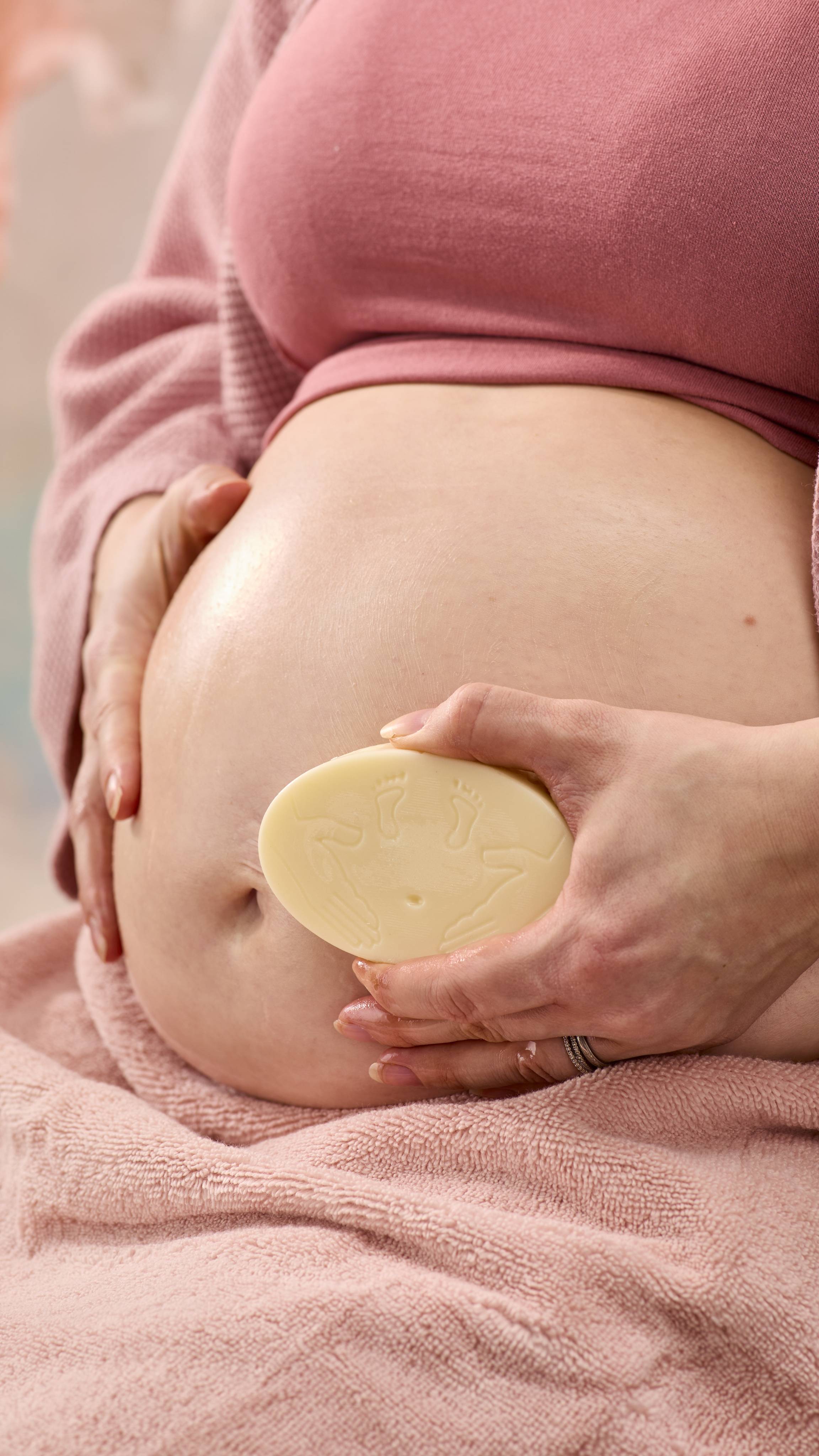 A close-up shot of the model's pregnant belly as they smooth over the moisturising The Bump solid massage bar over this skin.