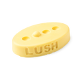 Therapy. A buttery yellow, oval shaped, solid massage bar, with a design of 3 small holes cut out with 1 bump in a line.