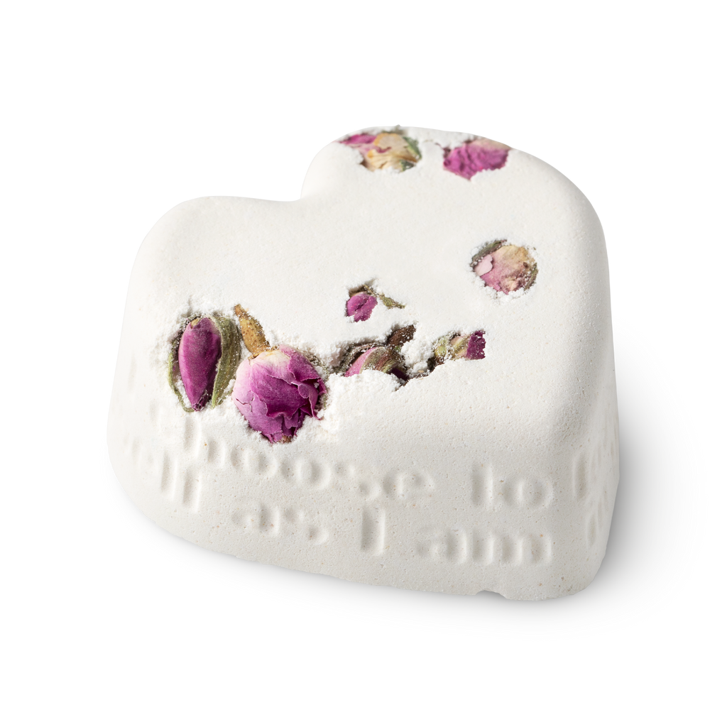 Tisty Tosty. A white, heart shaped bath bomb, topped with dried rosebuds, and a loving inscription running along its side edge.