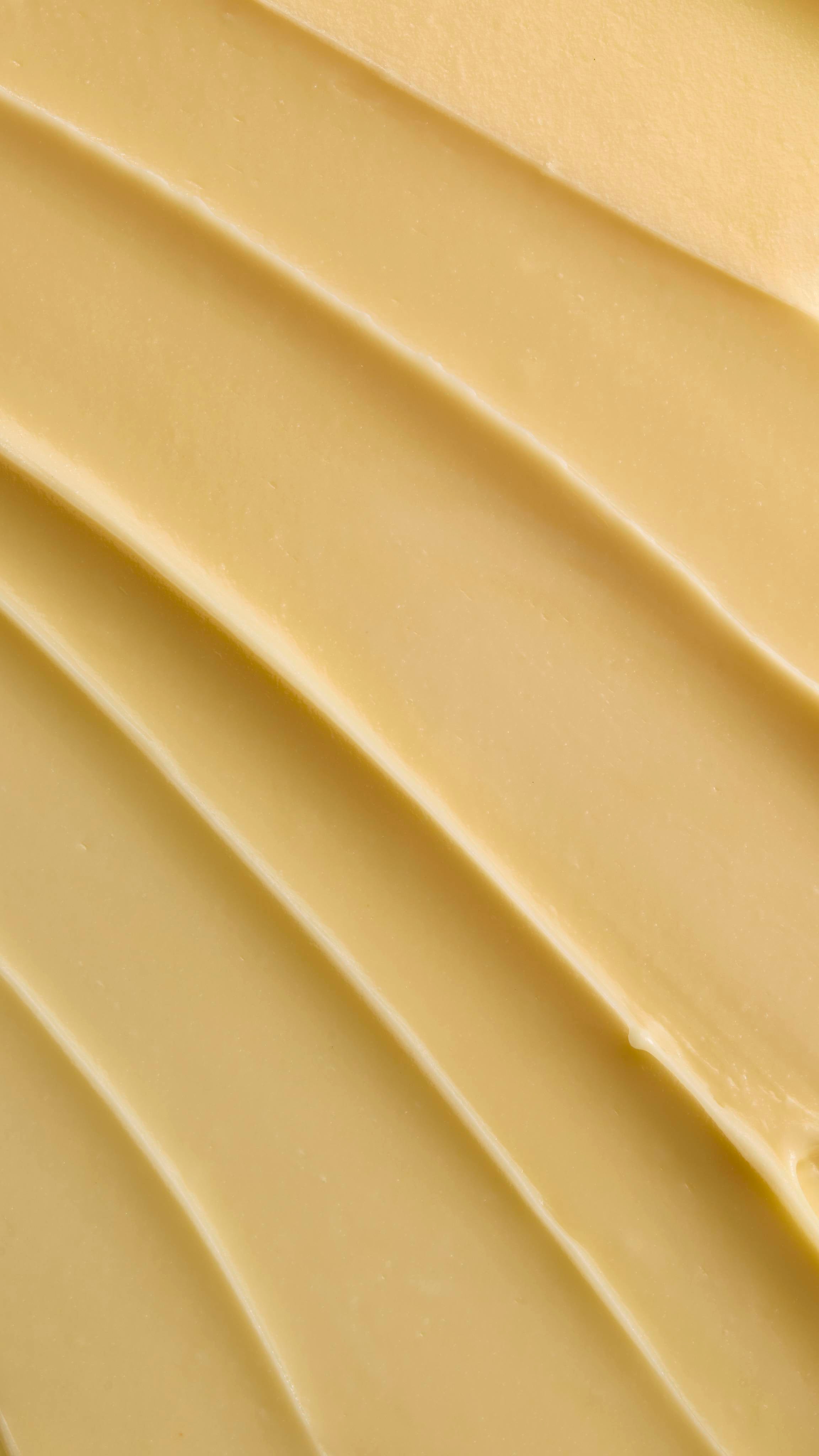 A close-up texture shot of pale yellow Ultrabland cleanser spread out in thick, smooth ridges, highlighting its rich and creamy consistency.
